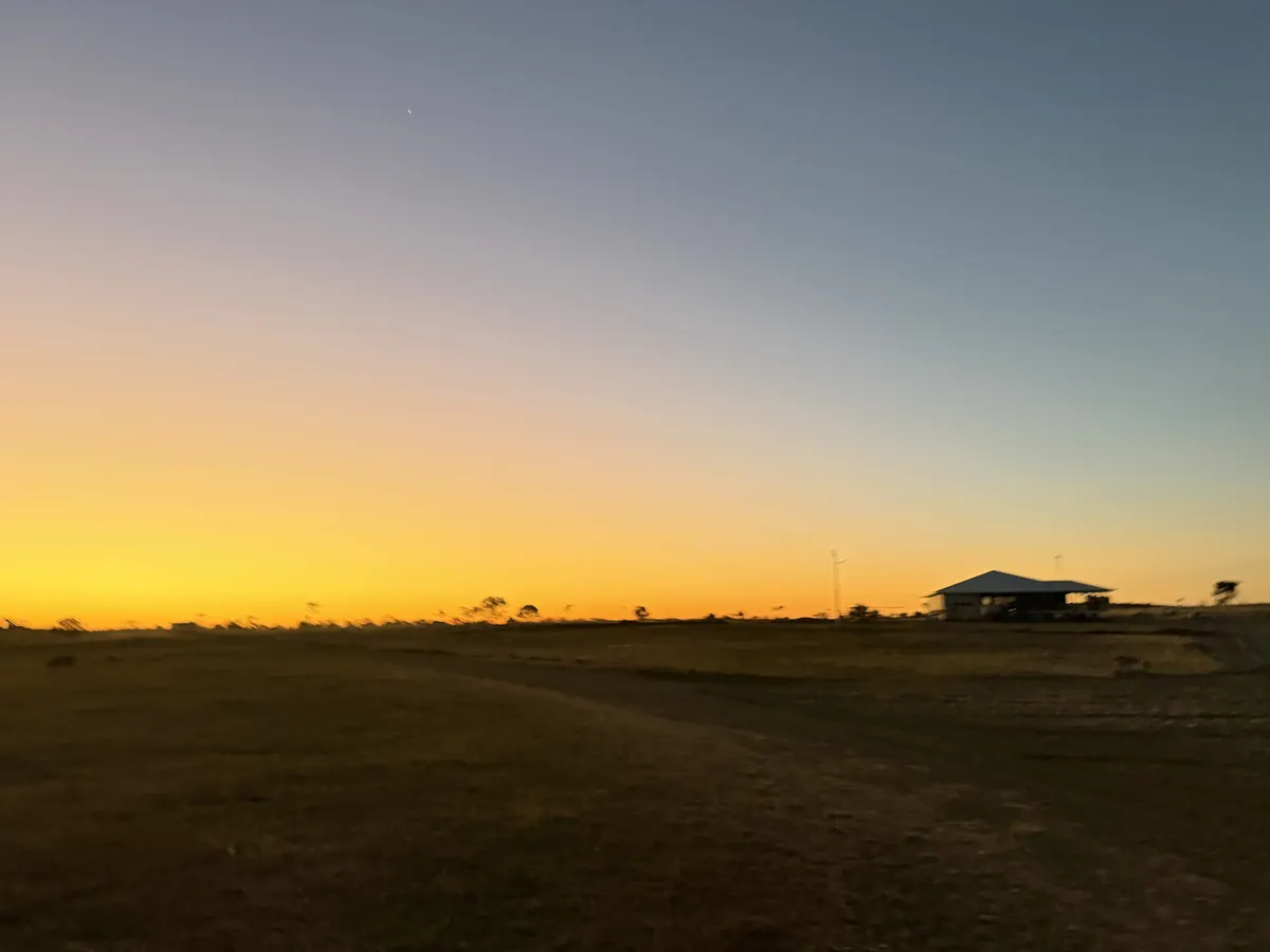 Dawn light over a flat horizon with a distant building