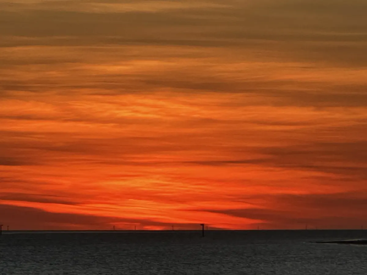 An orange sunset sky over still water